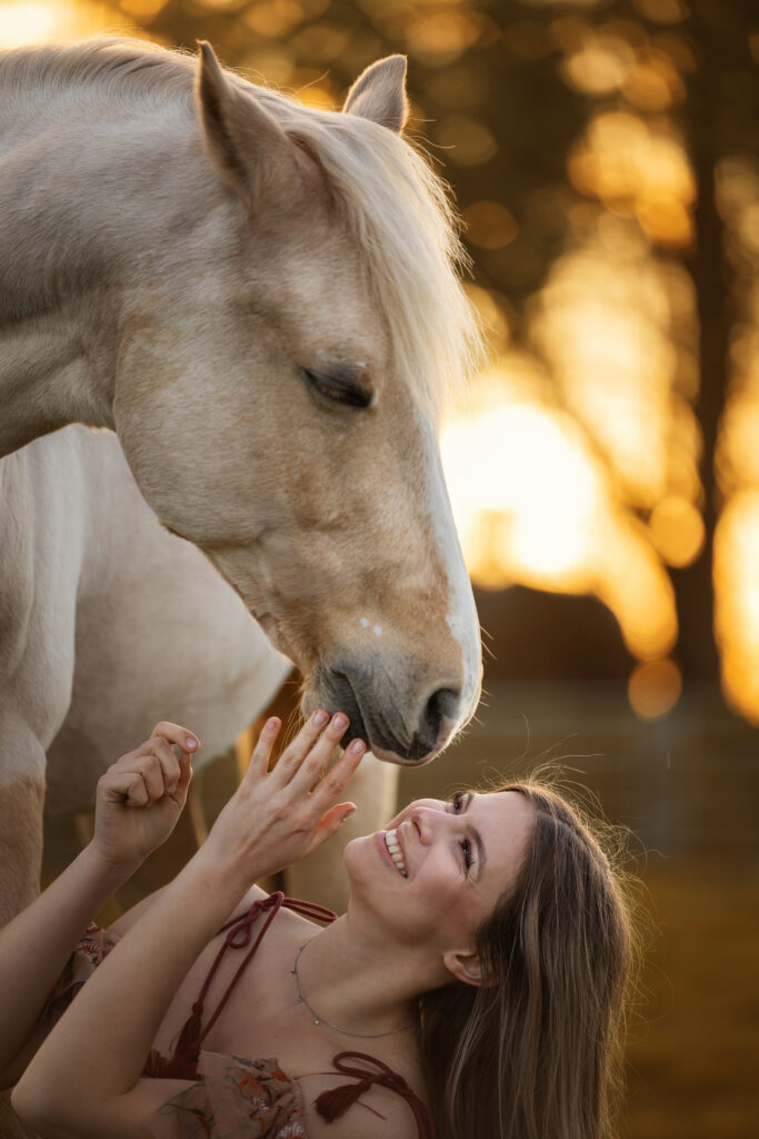 Junges Mädchen kuschelt mit ihrem Pferd beim Fotoshooting im Sonnenuntergang