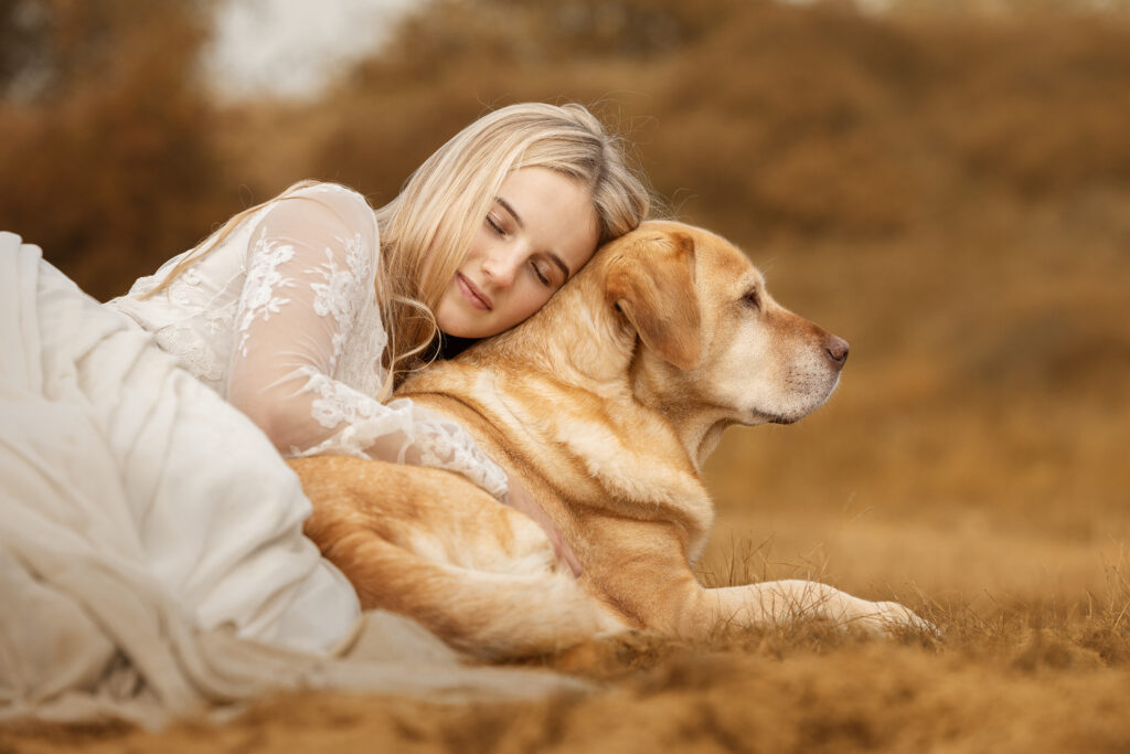 Junge Frau kuschelt mit blondem Labrador