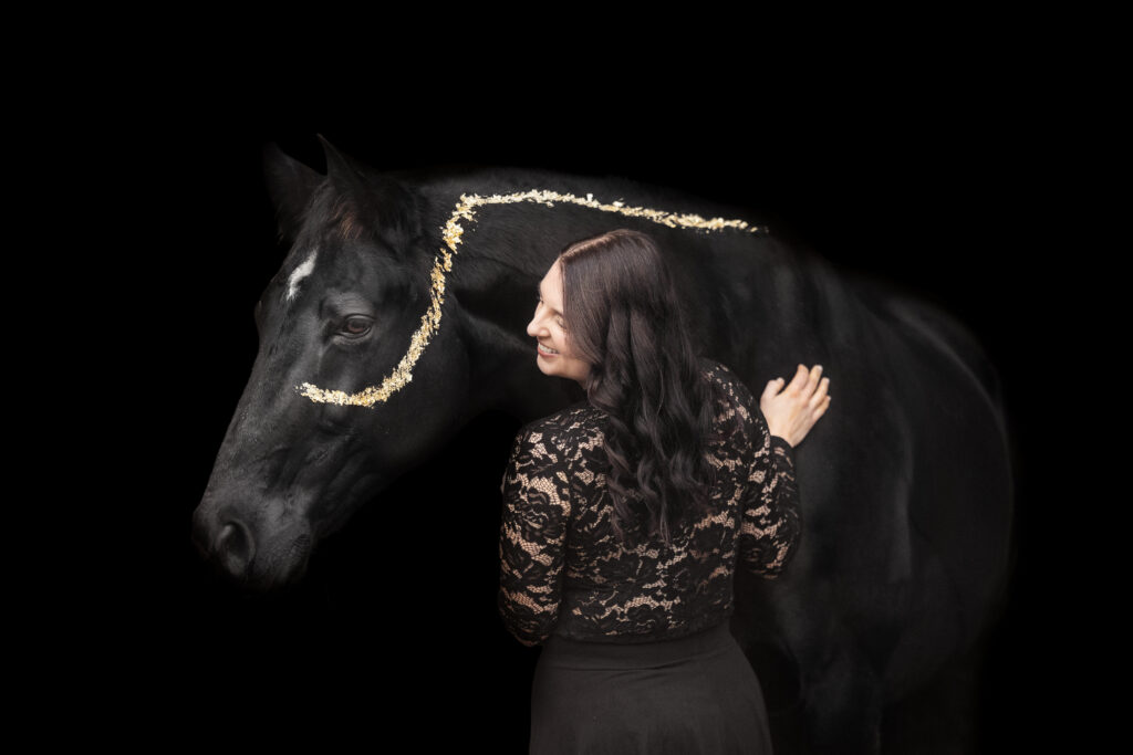 Frau mit Pferd beim Fotoshooting vor schwarzem Hintergrund mit Blattgold